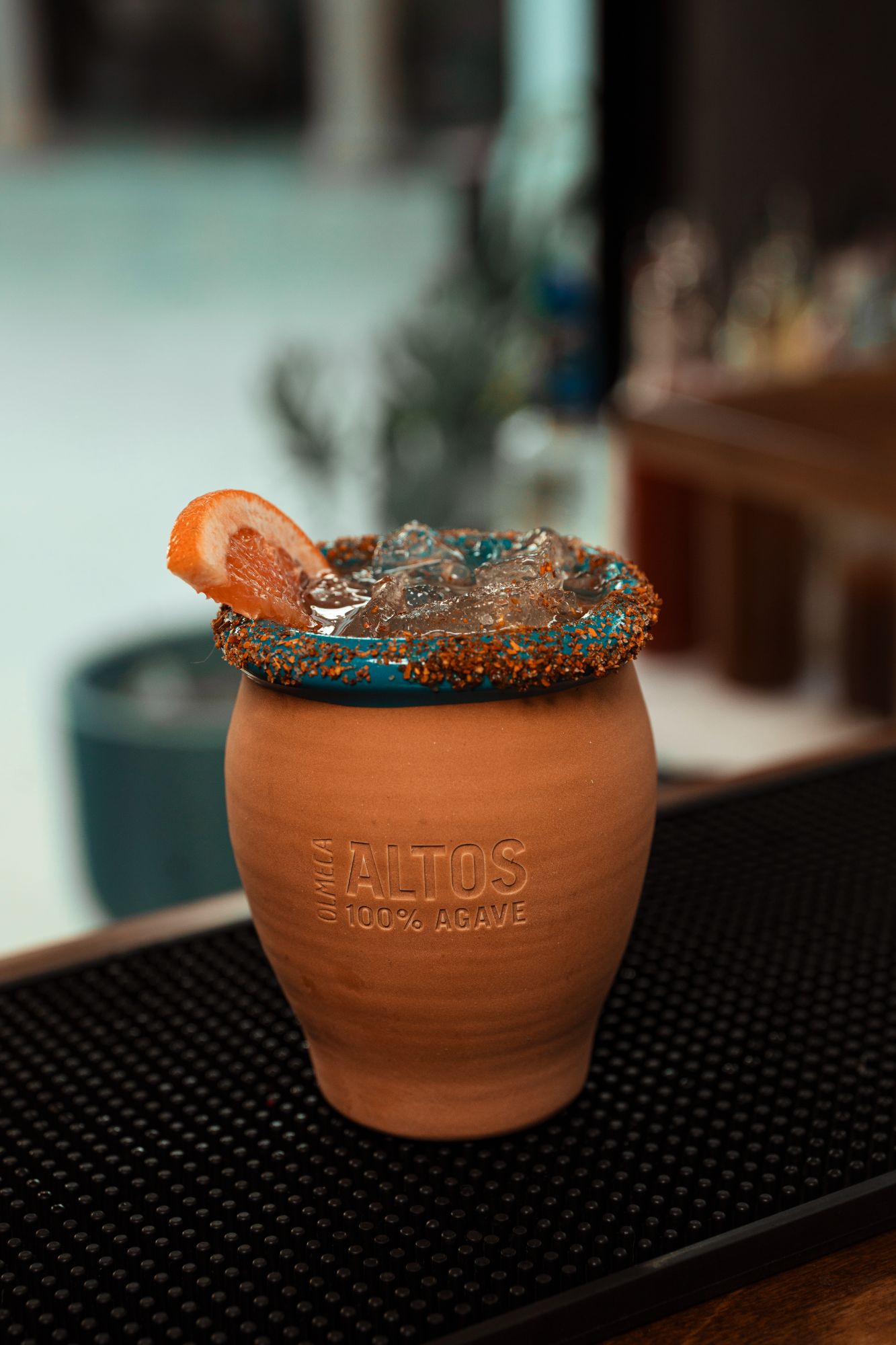 A grapefruit cooler served over ice in a terracotta agave mug with a chile-salt rim