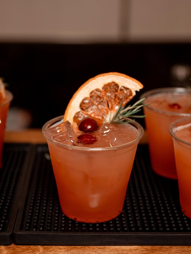A spiced cranberry paloma garnished with a dried grapefruit wheel, fresh cranberries and a sprig of rosemary