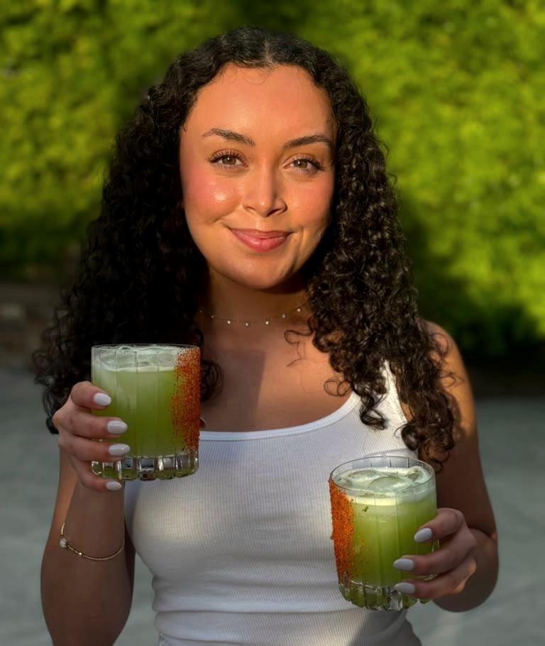 Nataly, founder of La Mezcla Mobile Bartending, holding two cocktails